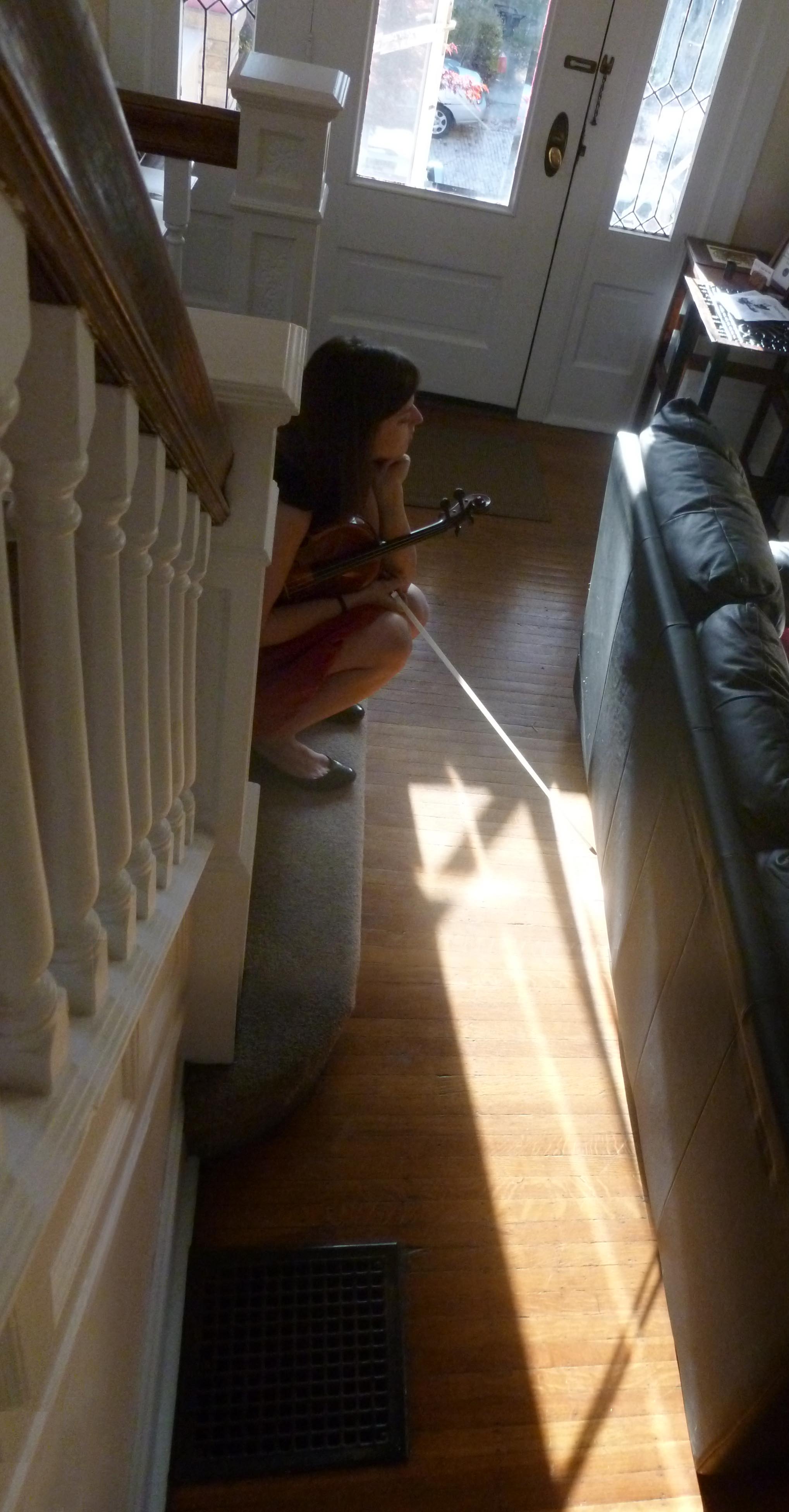 violinist sitting at bottom of stairs